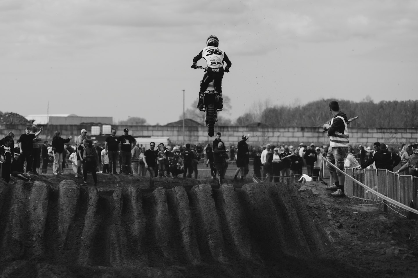 Motocross rider jumps a dirt bike over a large ramp.